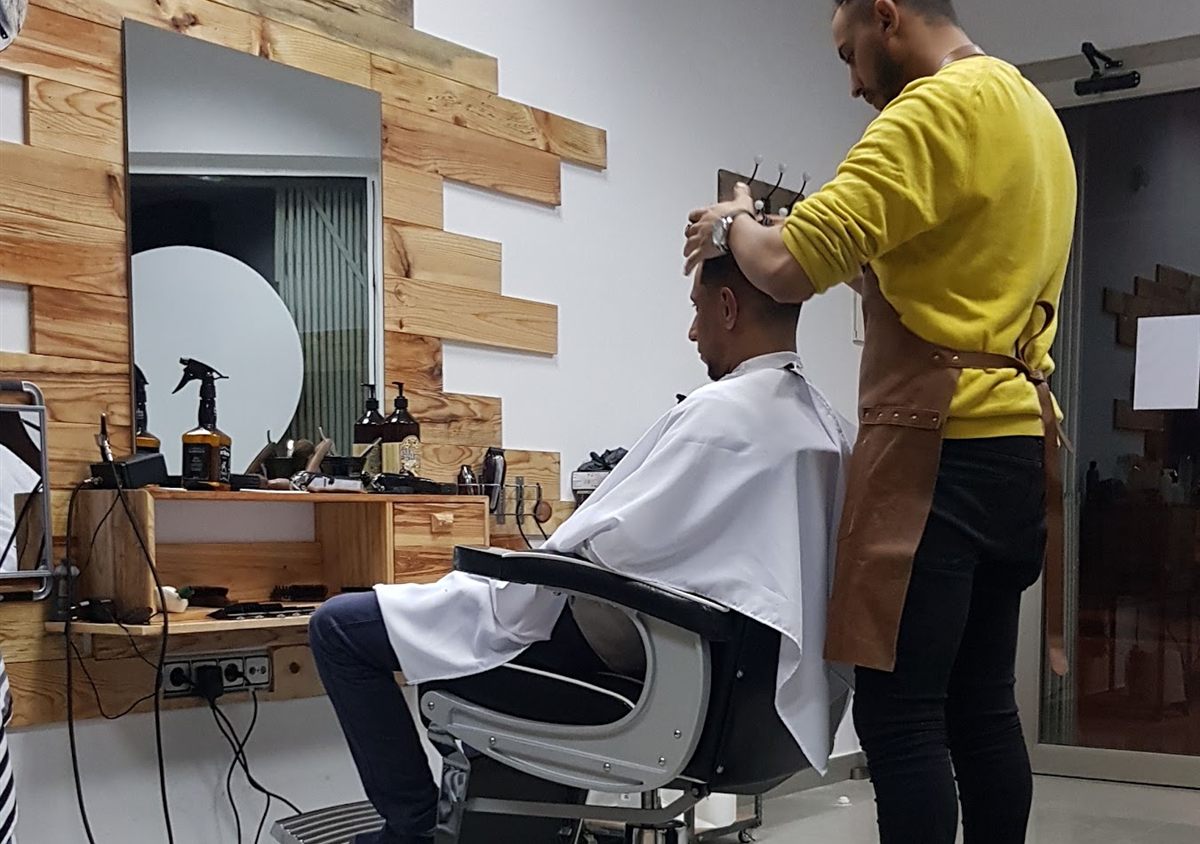 Yassine trabajando con el mandil de cuero frente al espejo de la barbería