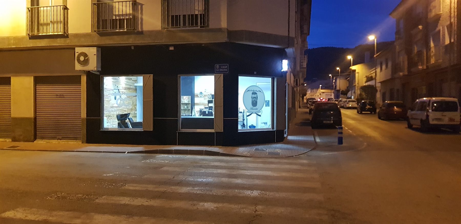 Fachada de Barbería The Bearded de noche, en la esquina de Collado Bermejo con La Encina